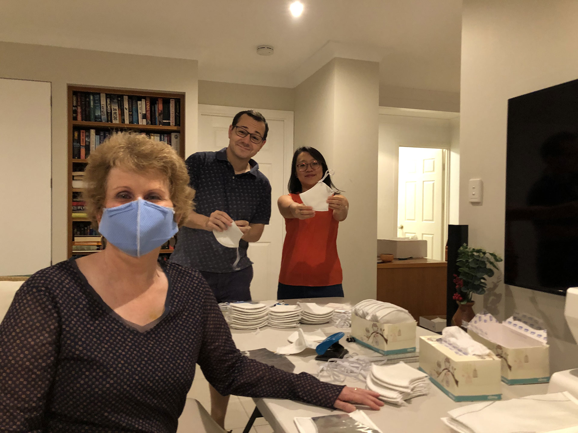 Dr Trish Baker (front) with son Robert Gallo and his fiancee Olivia Pratiwi with some of the DIY fabric face masks the family sewed together